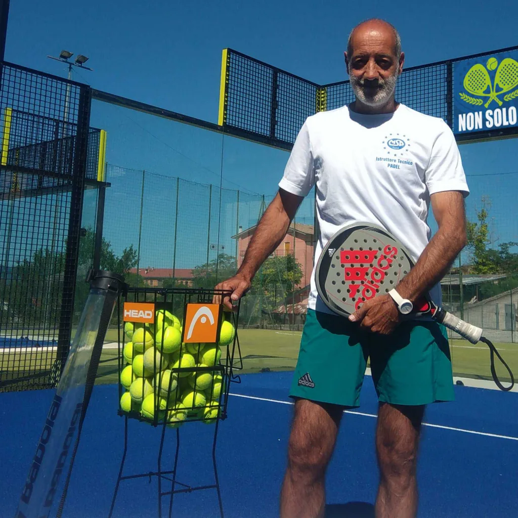 Spadolini Mario Spadolini con racchetta da padel accanto a un cesto di palline sul campo blu